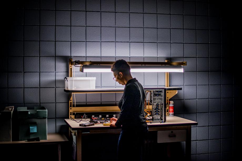 Student employee standing at a workbench and working with hard drives.