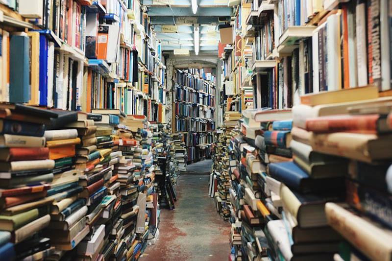 An aisle with books stacked from floor to ceiling on both sides.