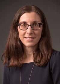 Photograph of Kristen Castellana, a white woman with dark brown hair and glasses