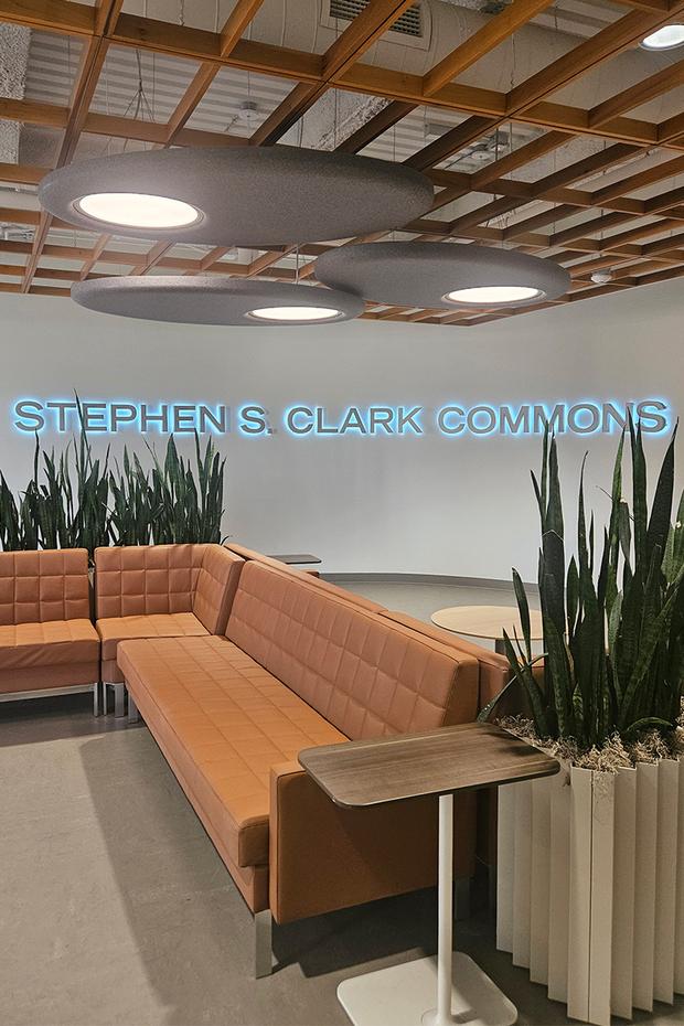 Welcoming seating area of the Stephen S. Clark Commons with the name on the wall, backlit.