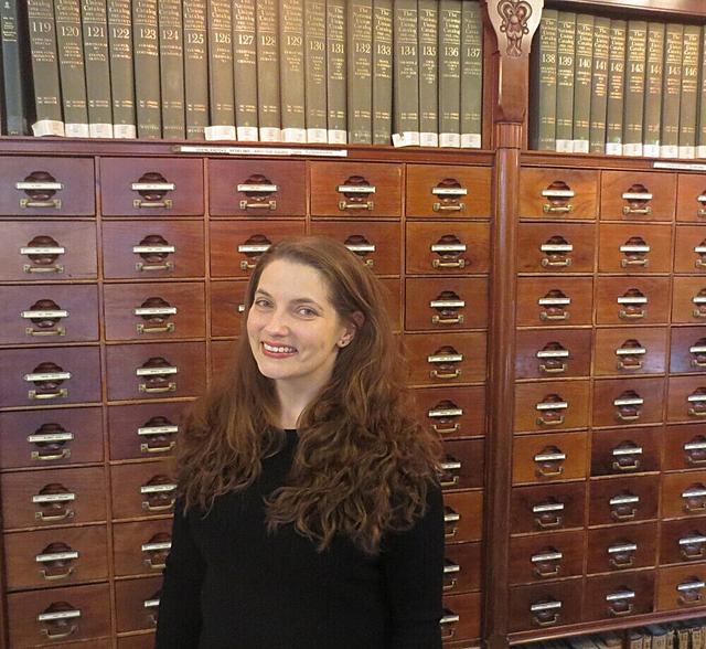 photo of Maura Seale, a smiling white woman with brown hair, standing in front of a physical card catalog