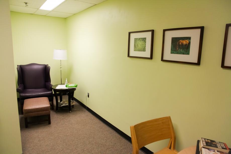 Corner space with a high-backed chair, footstool, side table and floor lamp.