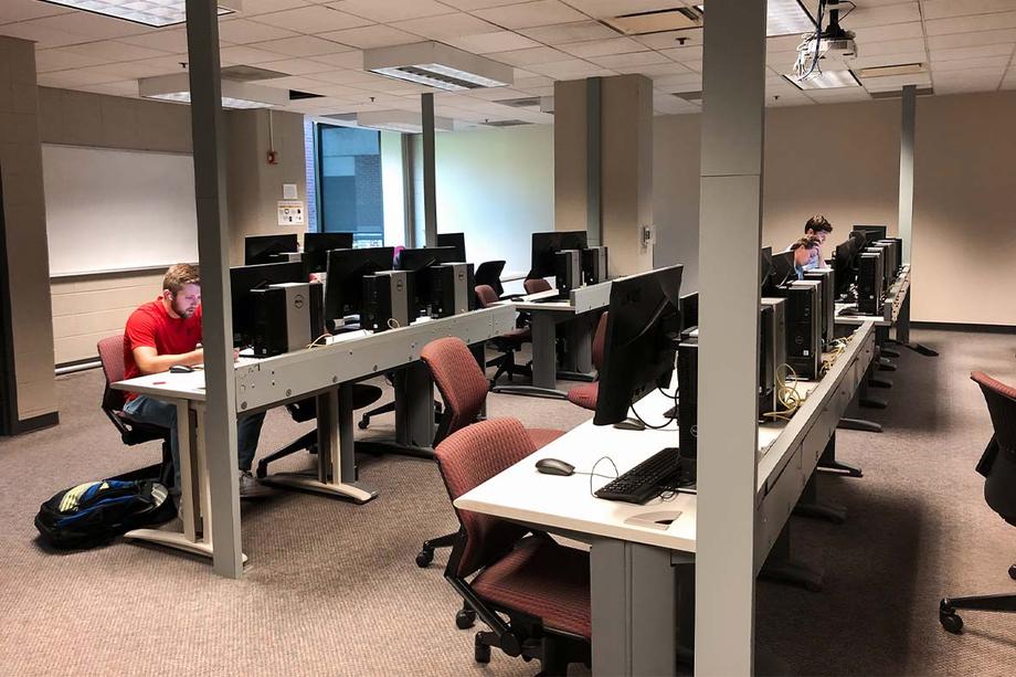 Students working in the computer lab where there are rows of computers.