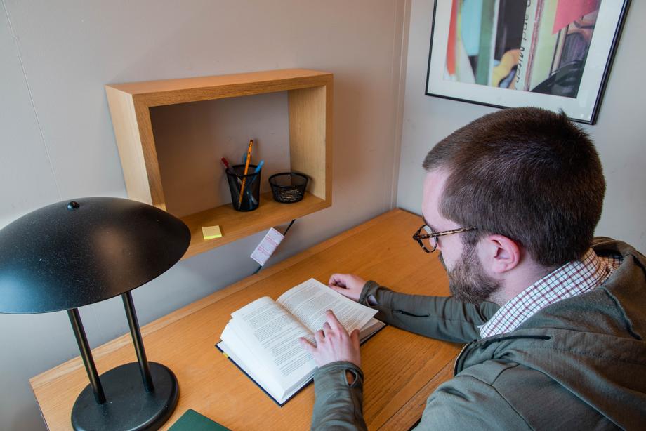 Close-up of a person sitting at the table in a carrel reading a book.